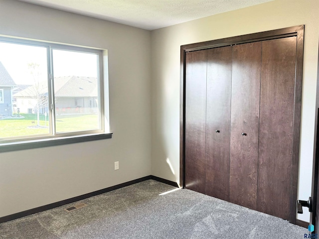 unfurnished bedroom featuring carpet, a textured ceiling, and a closet