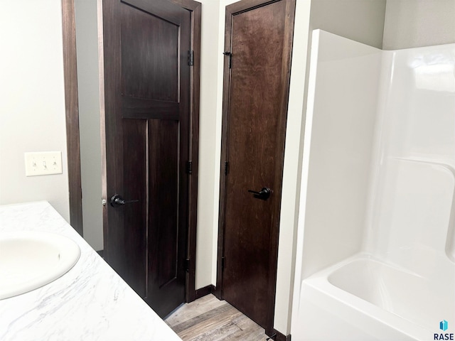 bathroom with hardwood / wood-style flooring, vanity, and  shower combination