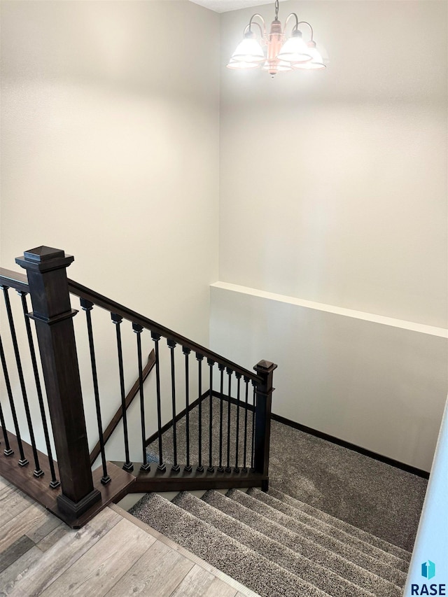 staircase with a chandelier and wood-type flooring