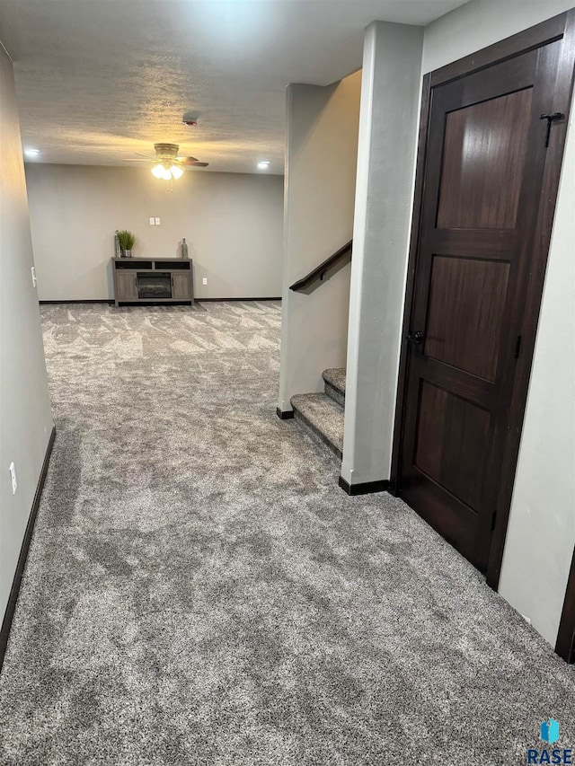 basement featuring ceiling fan, carpet, and a textured ceiling