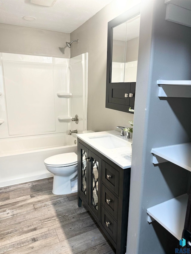 full bathroom with hardwood / wood-style floors, vanity, toilet, and  shower combination