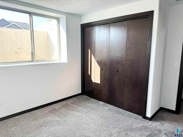 unfurnished bedroom with carpet, a textured ceiling, and a closet