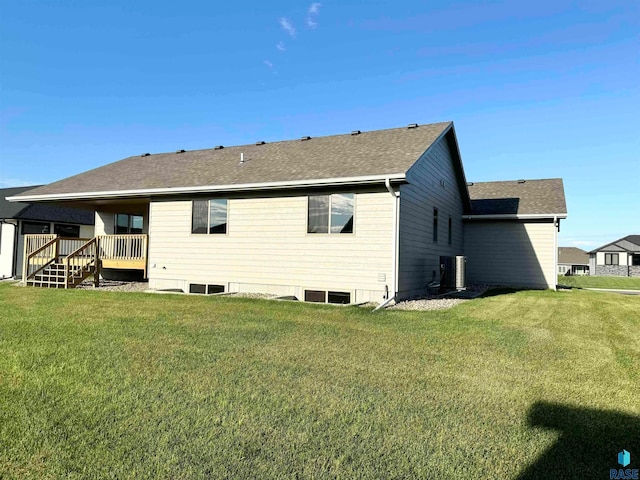 rear view of property featuring central air condition unit, a wooden deck, and a lawn