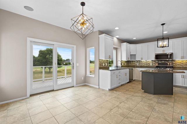 kitchen featuring white cabinetry, backsplash, appliances with stainless steel finishes, and decorative light fixtures