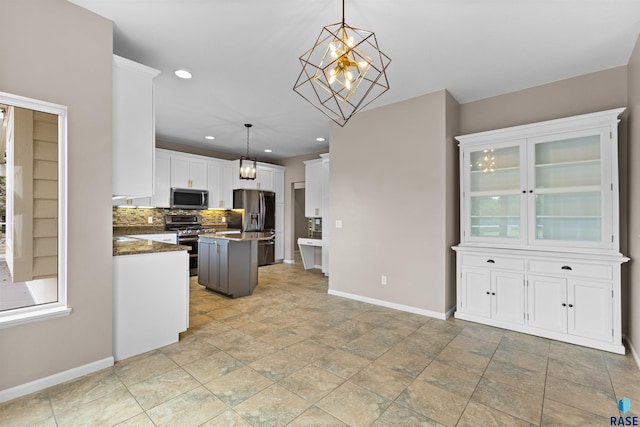 kitchen with appliances with stainless steel finishes, a kitchen island, backsplash, pendant lighting, and white cabinets