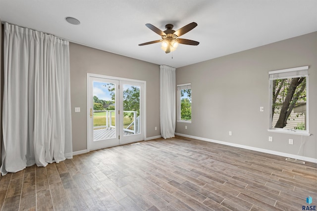 empty room with ceiling fan, a wealth of natural light, and hardwood / wood-style floors