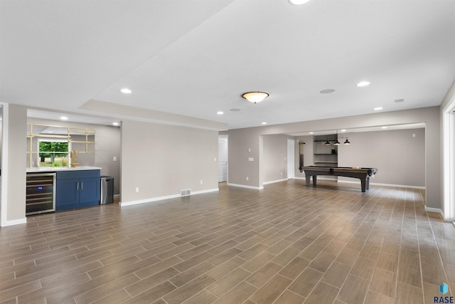 unfurnished living room featuring dark hardwood / wood-style floors, pool table, indoor bar, and beverage cooler