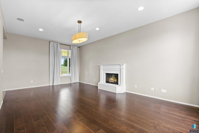 unfurnished living room with a premium fireplace and dark wood-type flooring