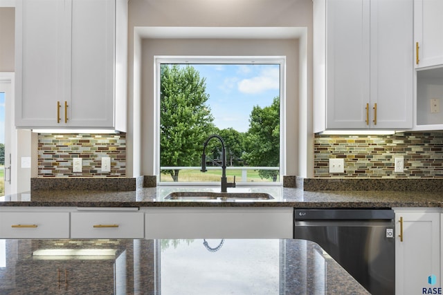 kitchen featuring sink, plenty of natural light, white cabinetry, dark stone counters, and stainless steel dishwasher