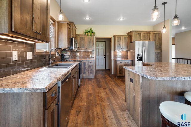 kitchen featuring stainless steel appliances, a center island, sink, and decorative light fixtures