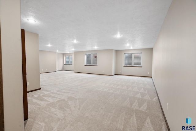 basement featuring light carpet and a textured ceiling