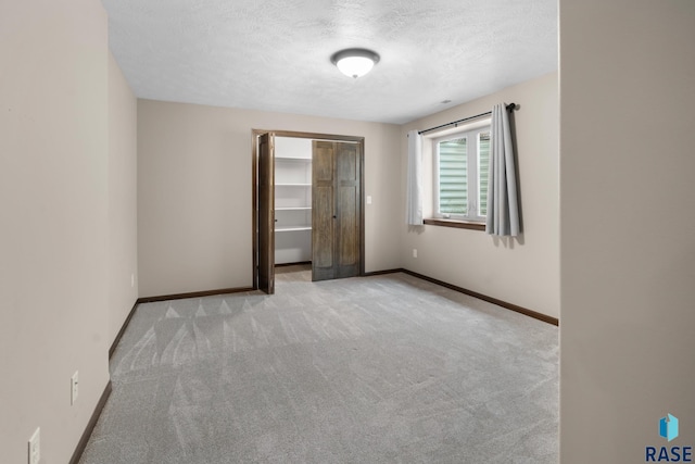 unfurnished bedroom with a closet, light carpet, and a textured ceiling