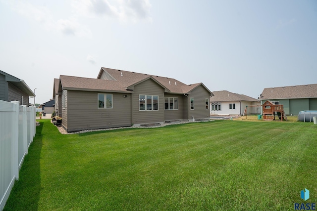 rear view of house with a lawn and a playground