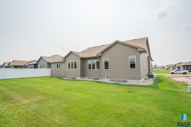 back of house with central AC unit and a yard