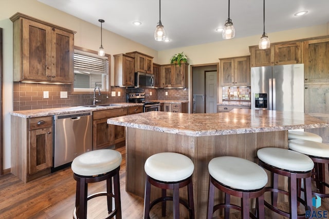 kitchen featuring sink, dark hardwood / wood-style floors, a kitchen island, pendant lighting, and stainless steel appliances