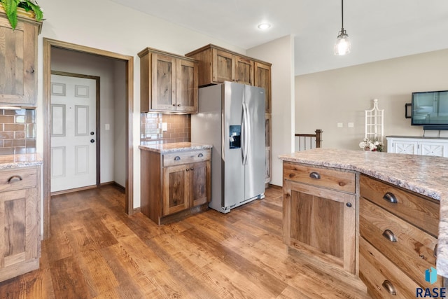 kitchen featuring pendant lighting, dark wood-type flooring, stainless steel fridge with ice dispenser, and tasteful backsplash