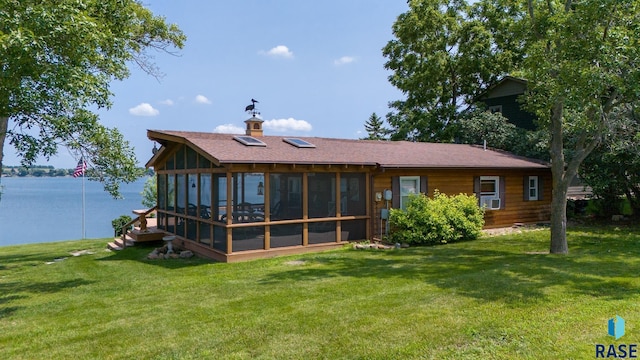 back of house featuring a water view, a sunroom, and a lawn