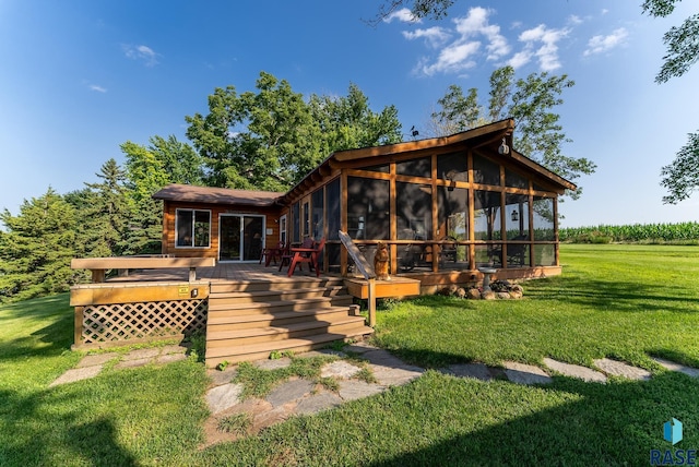 back of house with a deck, a lawn, and a sunroom