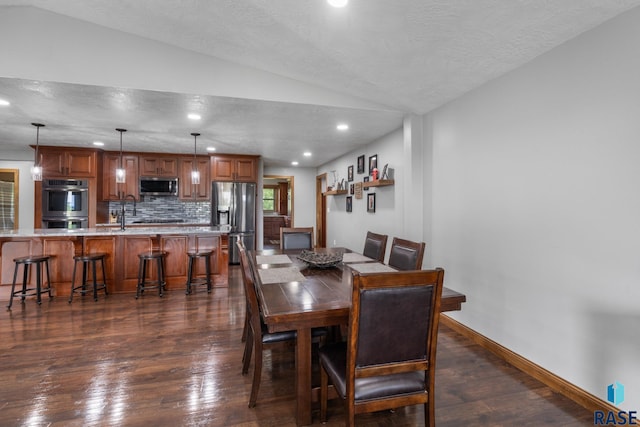 dining space with lofted ceiling, a textured ceiling, sink, and dark wood-type flooring