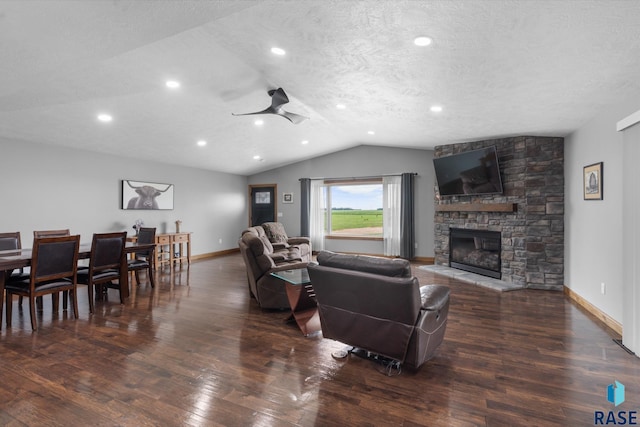 living room with ceiling fan, a textured ceiling, vaulted ceiling, dark hardwood / wood-style floors, and a fireplace