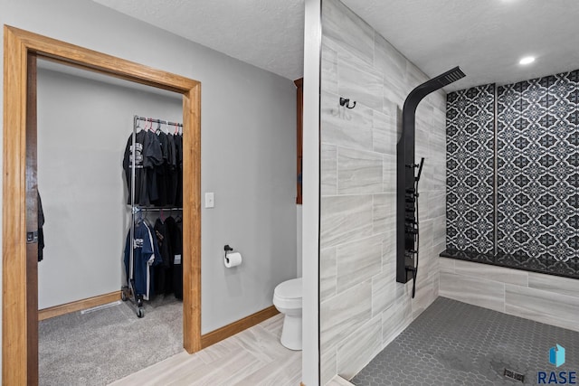 bathroom featuring toilet, a textured ceiling, and tiled shower