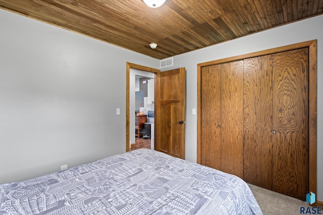 carpeted bedroom featuring a closet and wooden ceiling