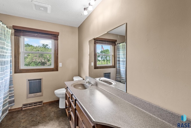 bathroom featuring a healthy amount of sunlight, vanity, heating unit, and toilet