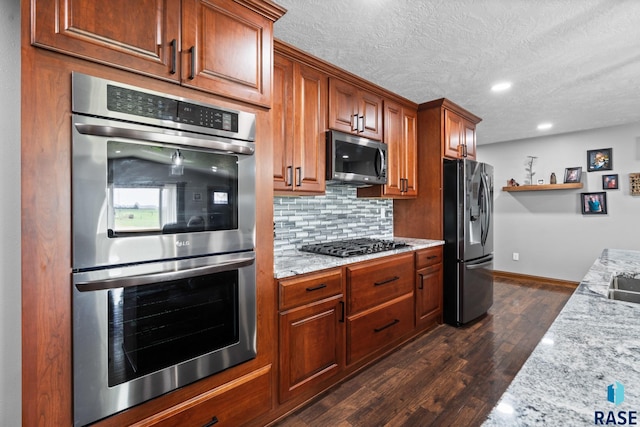 kitchen with dark wood-type flooring, light stone countertops, decorative backsplash, and stainless steel appliances