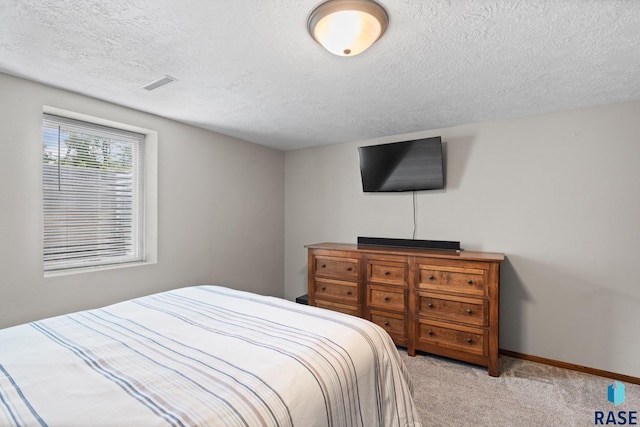 bedroom with a textured ceiling and light colored carpet