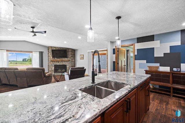 kitchen featuring light stone countertops, sink, a textured ceiling, decorative light fixtures, and dark wood-type flooring