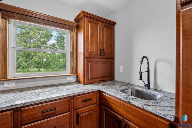 kitchen featuring a textured ceiling, light stone countertops, and sink