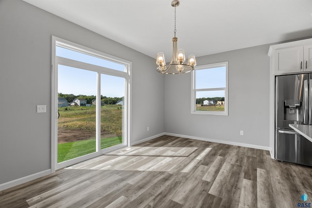 unfurnished dining area with light hardwood / wood-style flooring, a wealth of natural light, and a chandelier