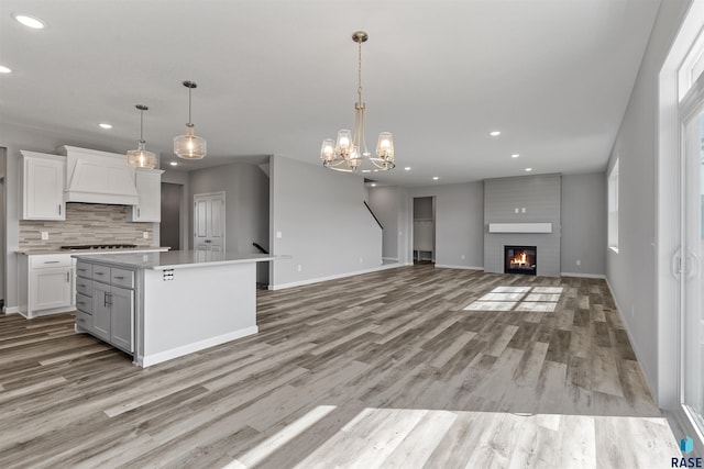 kitchen with a kitchen island, white cabinetry, a fireplace, and pendant lighting