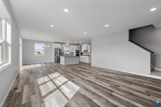 unfurnished living room with light hardwood / wood-style flooring and an inviting chandelier