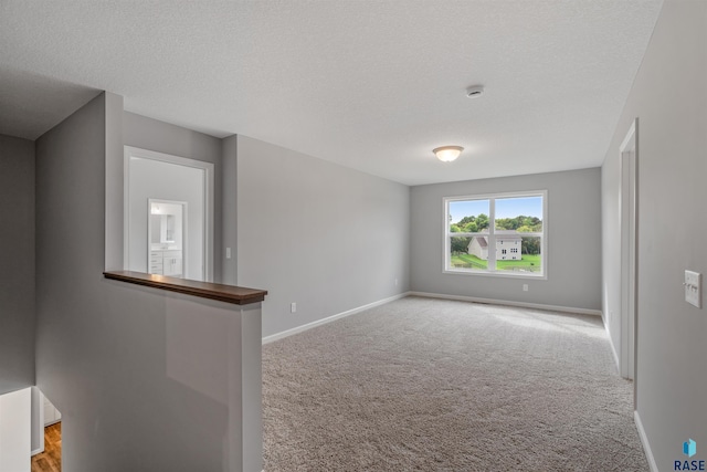 spare room with light carpet and a textured ceiling