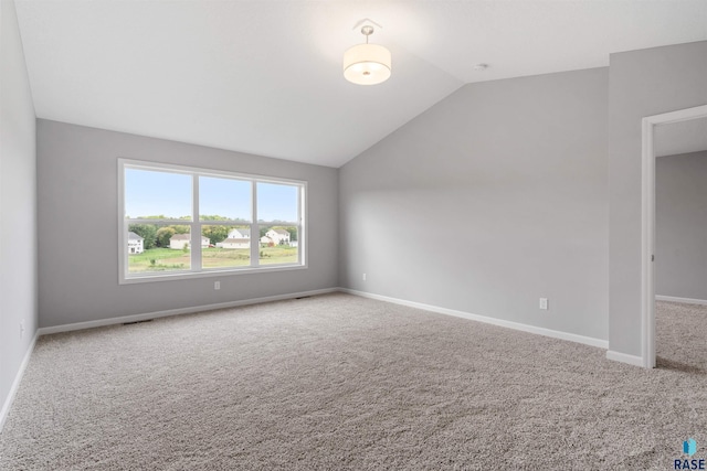 carpeted empty room with lofted ceiling