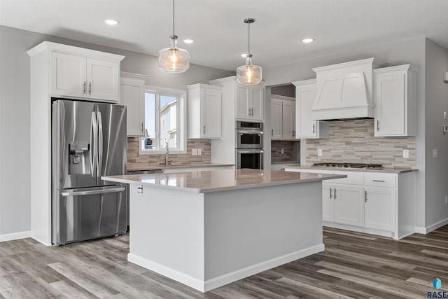 kitchen featuring pendant lighting, white cabinetry, custom range hood, and stainless steel appliances