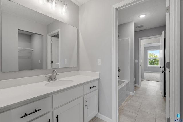 bathroom featuring vanity, a tub to relax in, a textured ceiling, and tile patterned flooring