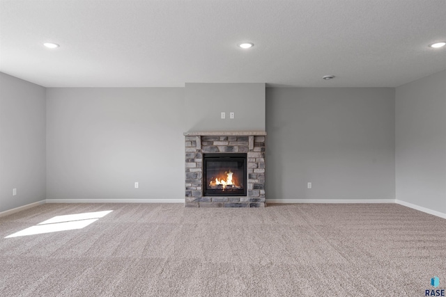 unfurnished living room with light carpet, a textured ceiling, and a stone fireplace