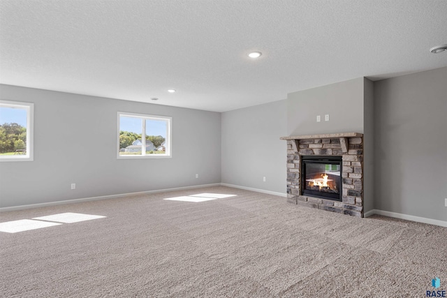 unfurnished living room with a fireplace, carpet floors, a textured ceiling, and plenty of natural light