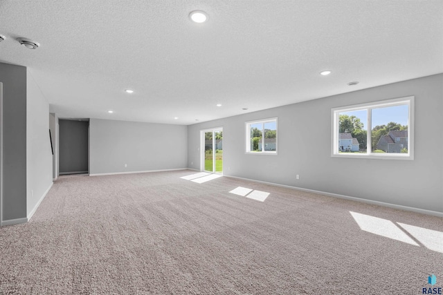 spare room featuring a textured ceiling and light colored carpet