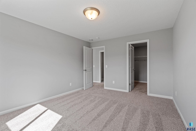 unfurnished bedroom with a closet, light colored carpet, and a walk in closet