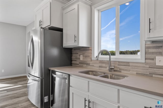 kitchen with decorative backsplash, white cabinetry, light wood-type flooring, sink, and stainless steel appliances