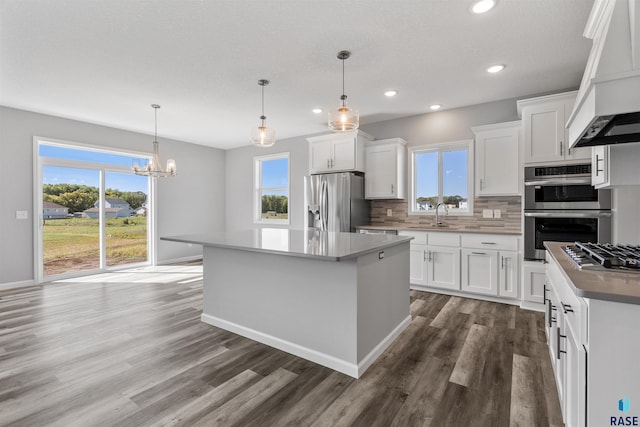 kitchen featuring white cabinetry, a center island, hanging light fixtures, and plenty of natural light