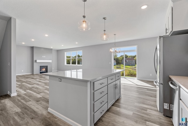 kitchen with hanging light fixtures, a wealth of natural light, a large fireplace, and a kitchen island