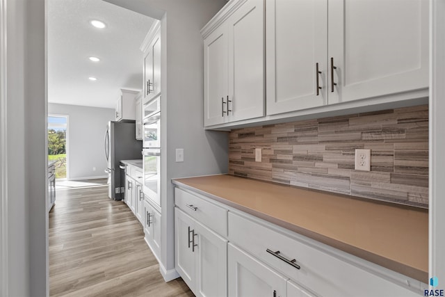 kitchen featuring stainless steel refrigerator, light hardwood / wood-style flooring, and white cabinets