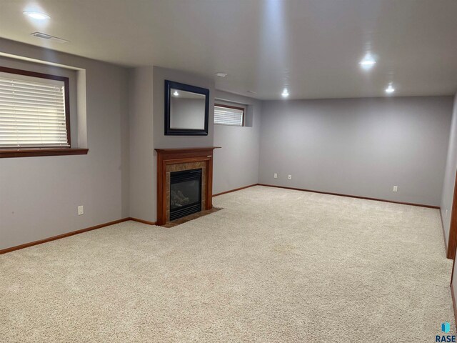 unfurnished living room with light carpet and a tiled fireplace