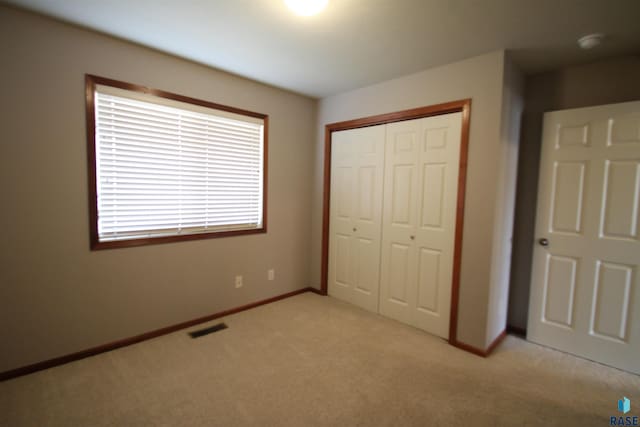 unfurnished bedroom with a closet and light colored carpet