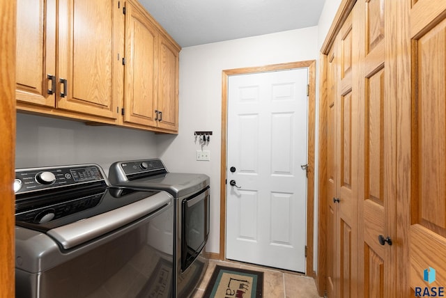 laundry room with cabinets, light tile patterned flooring, and washing machine and dryer