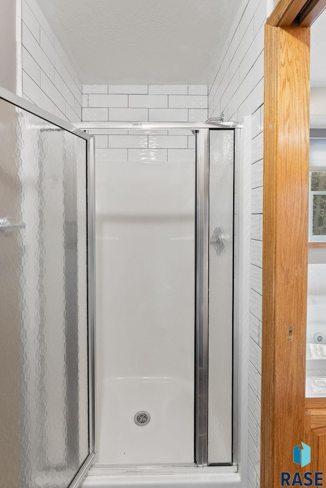 bathroom featuring a textured ceiling and a shower with shower door